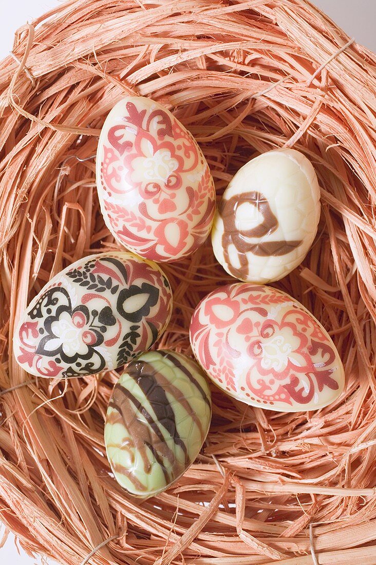 Decorated chocolate eggs in Easter nest (overhead view)