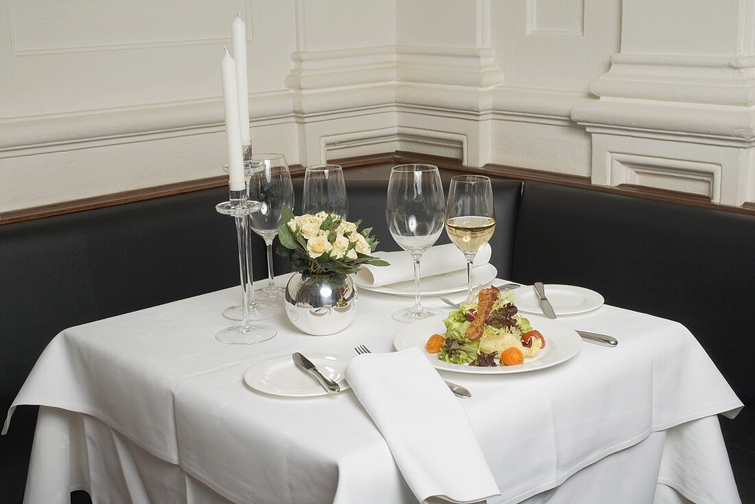 Gedeckter Tisch mit Salat und Weißwein im Restaurant