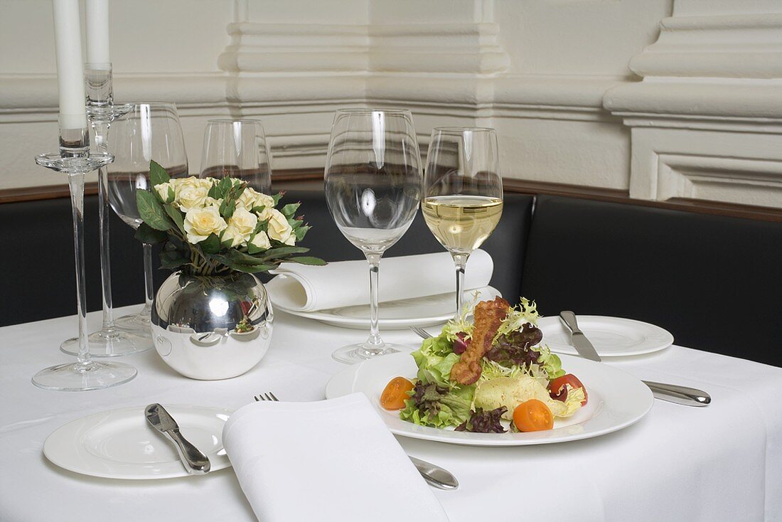 Gedeckter Tisch mit Salat und Weißwein im Restaurant