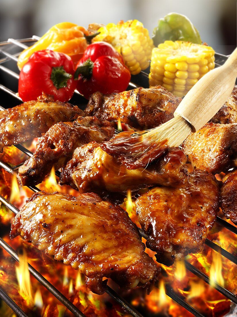 Brushing chicken wings on barbecue rack with marinade