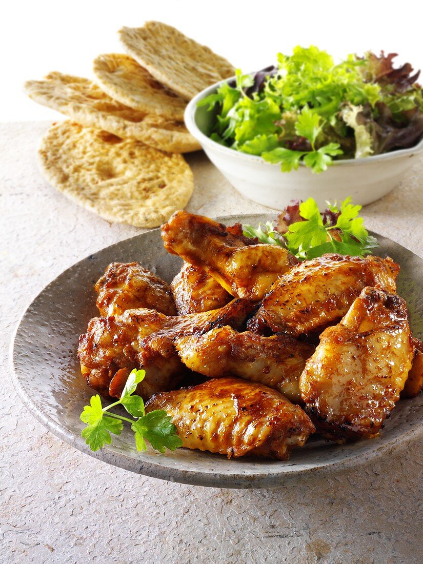 Grilled chicken wings with salad leaves and bread
