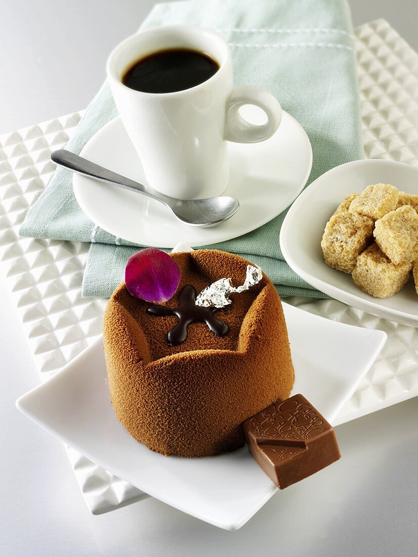 Small chocolate cake, cup of coffee and sugar cubes