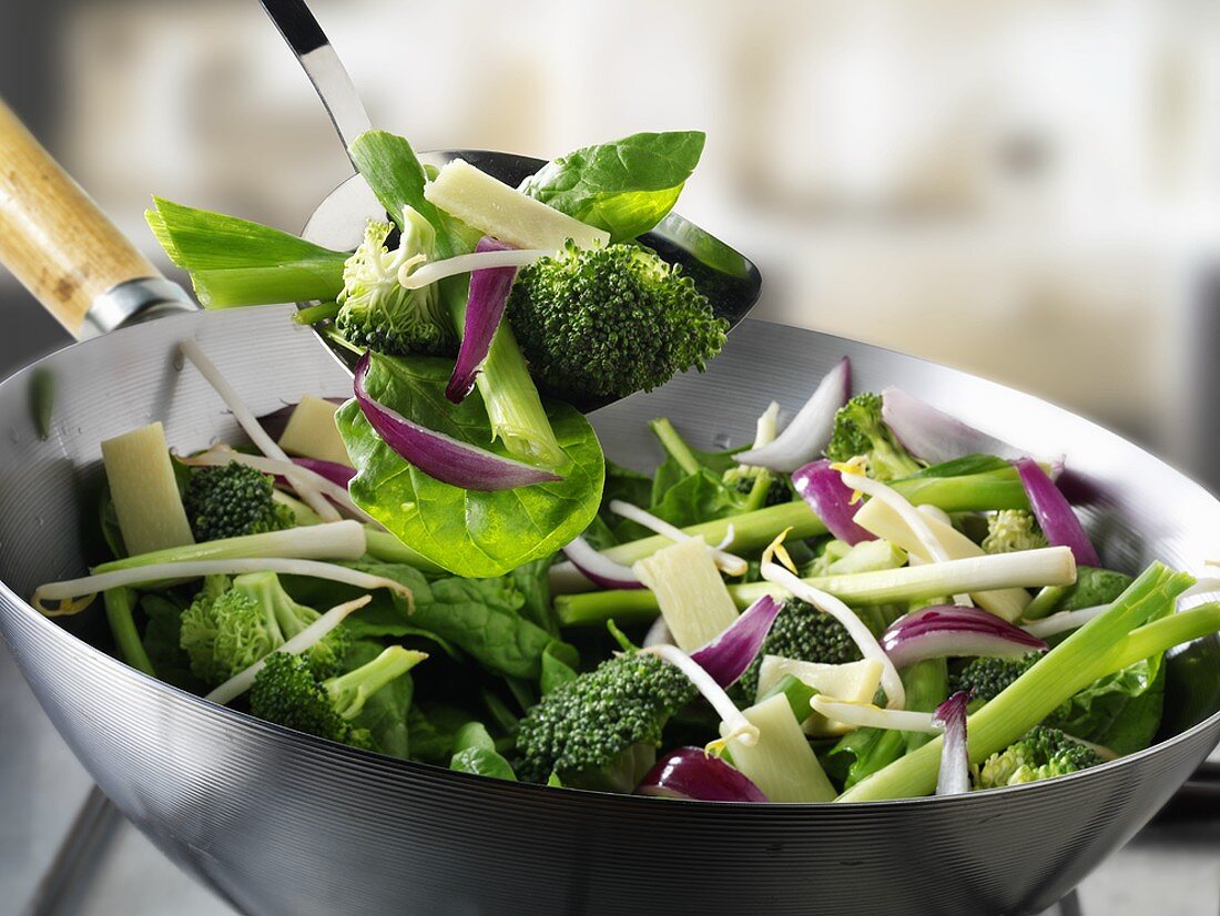 Green vegetables in wok and on spatula