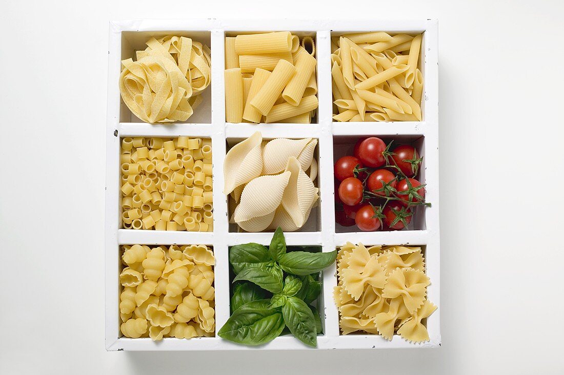 Various types of pasta, tomatoes and basil in type case