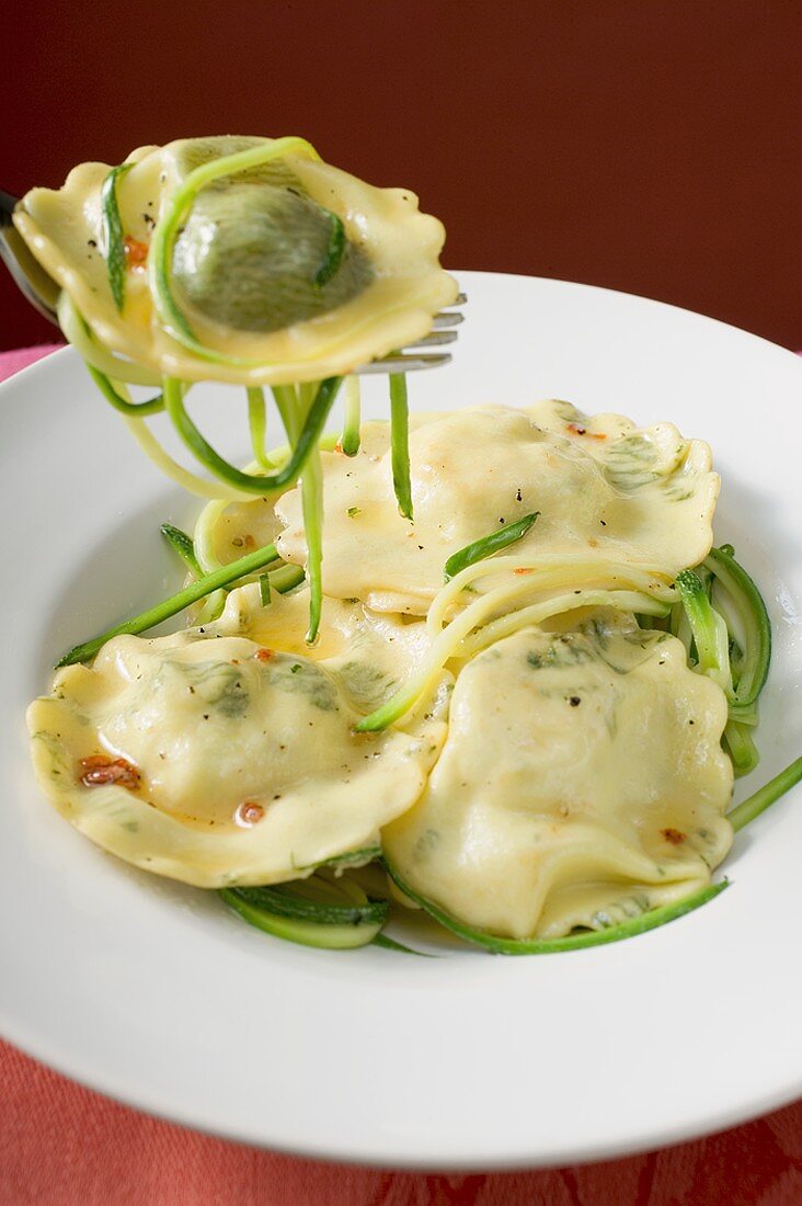 Ravioli mit Zucchinistreifen auf Teller und Gabel