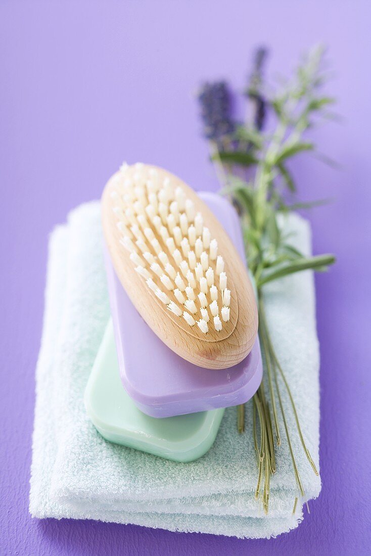 Brush and bars of soap on towel, sprig of lavender