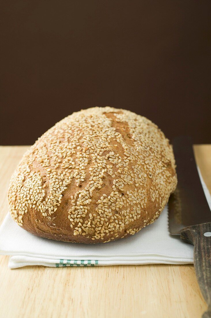 Sesame bread on tea towel with bread knife