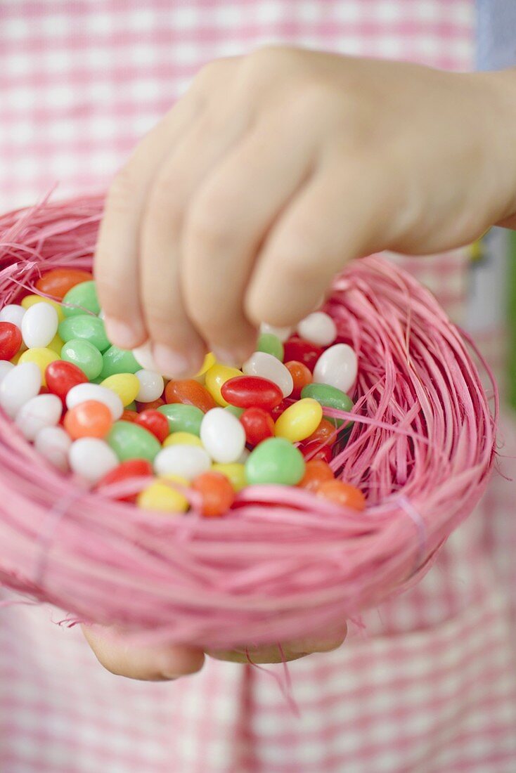 Child's hands holding Easter nest full of coloured sugar eggs