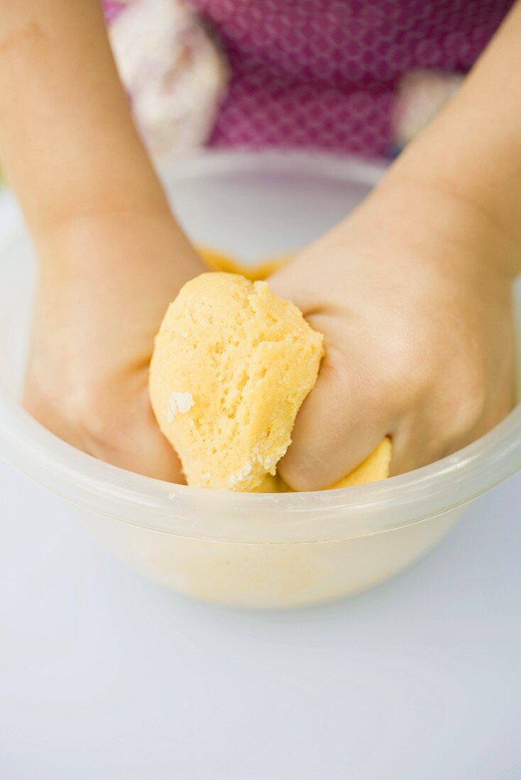 Child's hands kneading dough