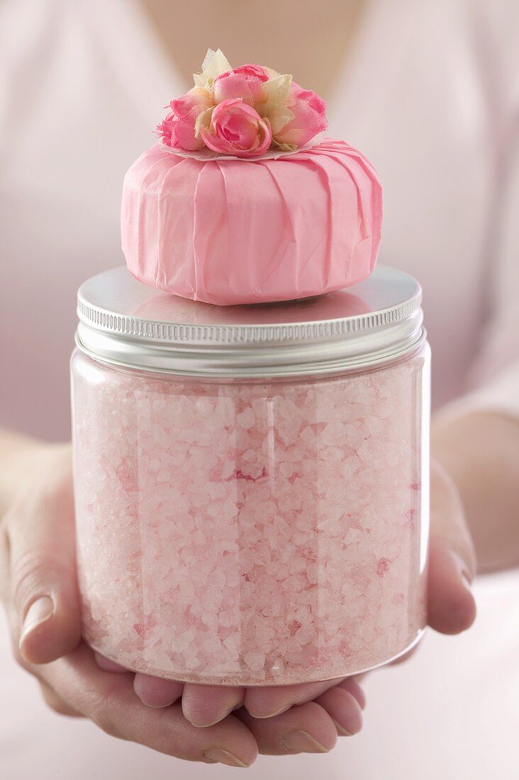 Hands holding pink bath salts and scented soap