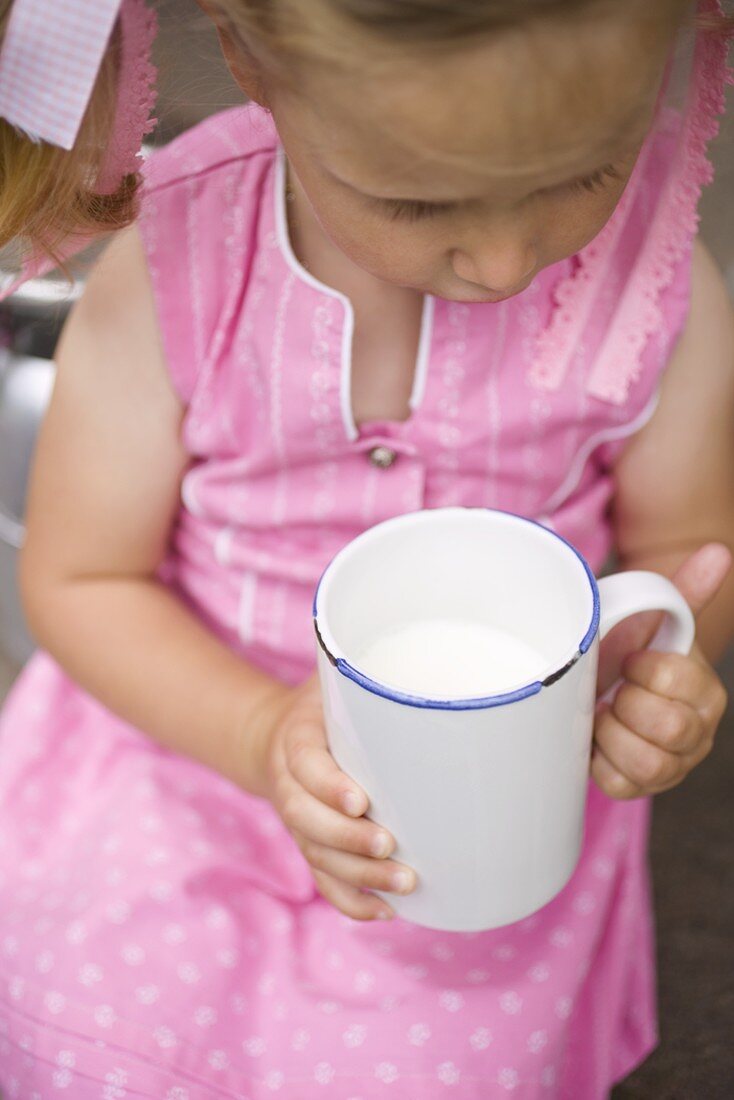 Small girl holding mug of milk