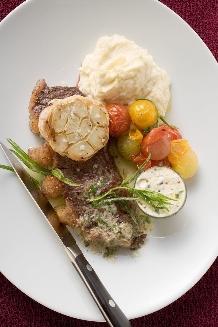 Beef steak with garlic, cherry tomatoes and mashed potato