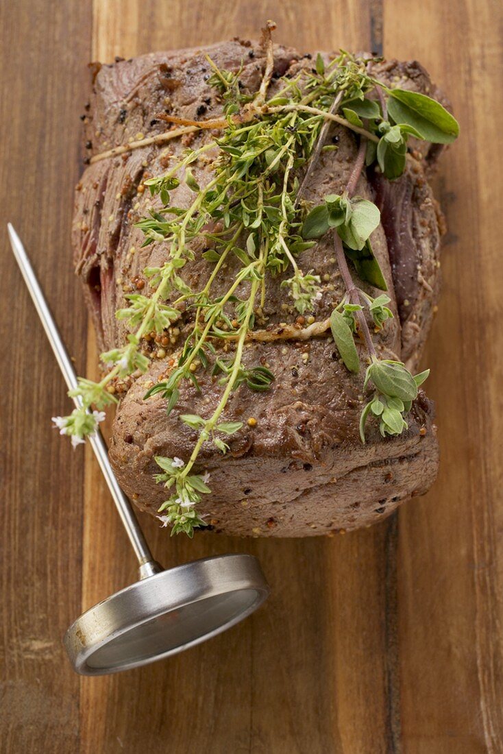 Roast beef with herbs, meat thermometer (overhead view)