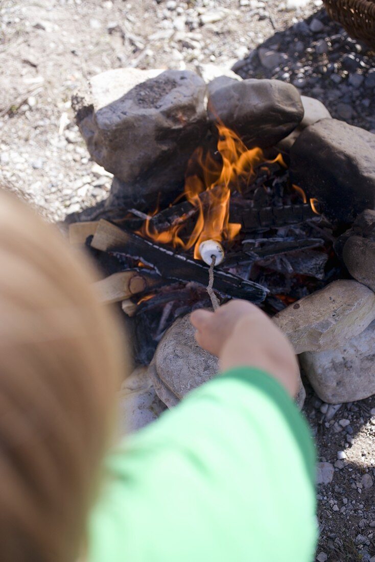 Kind grillt Marshmallows am Lagerfeuer