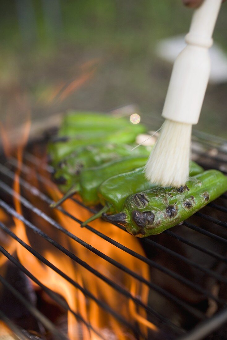 Green chillies on barbecue grill rack with brush