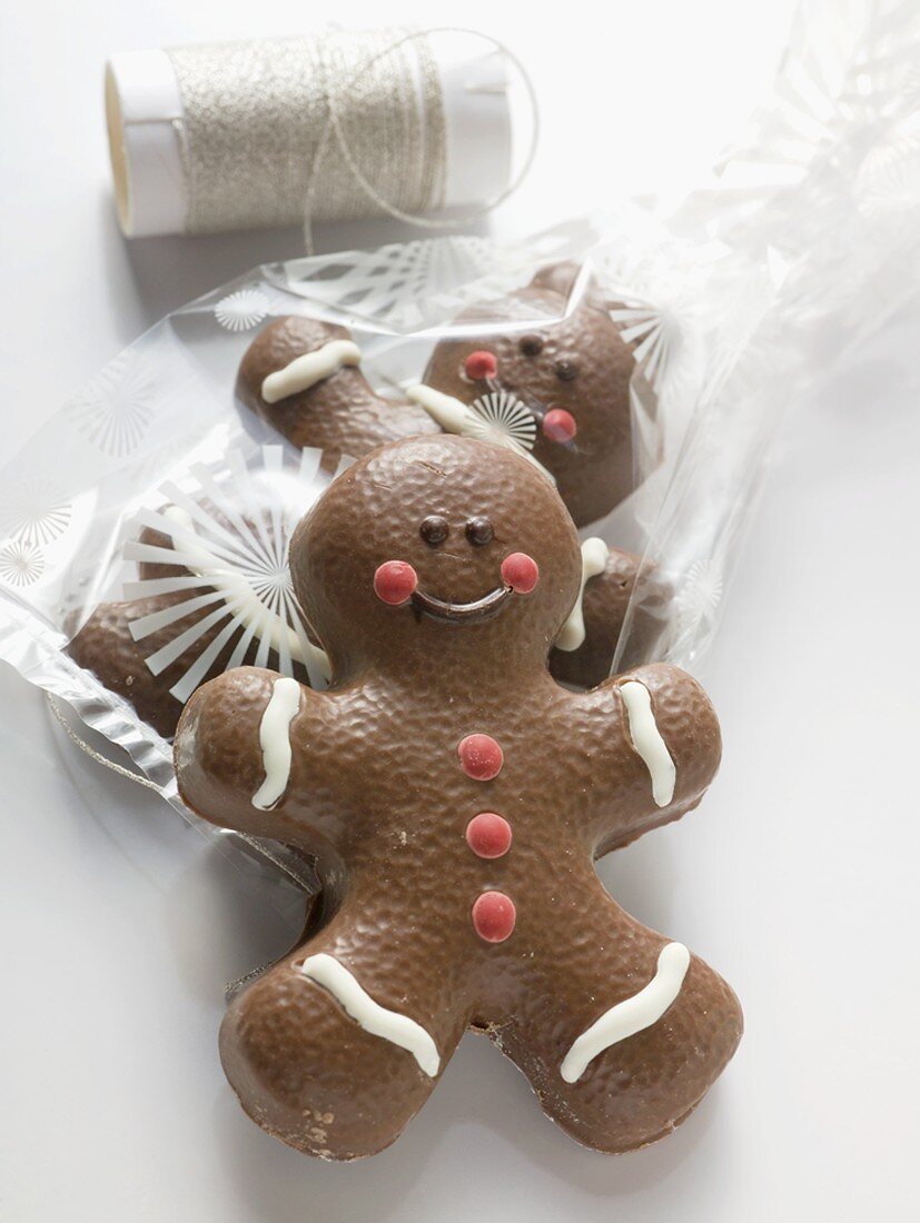 Two chocolate-coated gingerbread men, one in cellophane bag