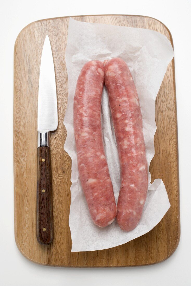 Two sausages on paper on chopping board