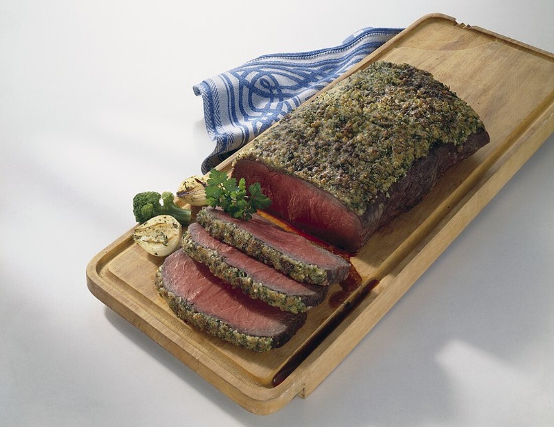 Roast beef with herb crust on chopping board