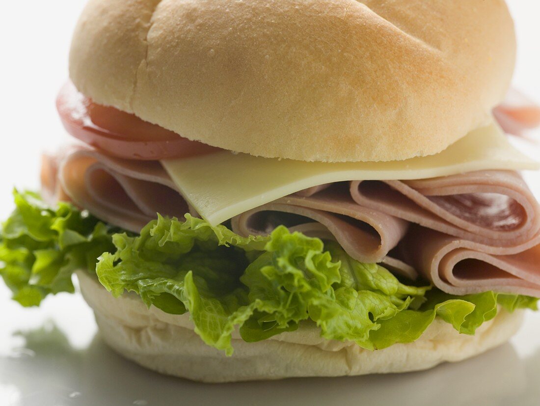 Bread roll filled with ham, cheese, lettuce & tomato (close-up)