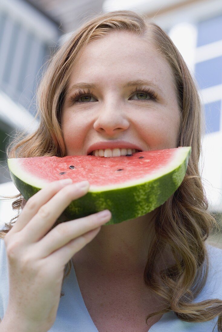 Junge Frau beisst in Wassermelone