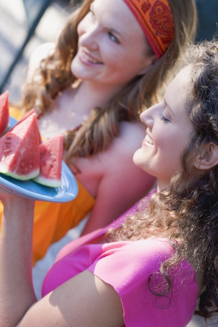 Two young women with wedges of watermelon