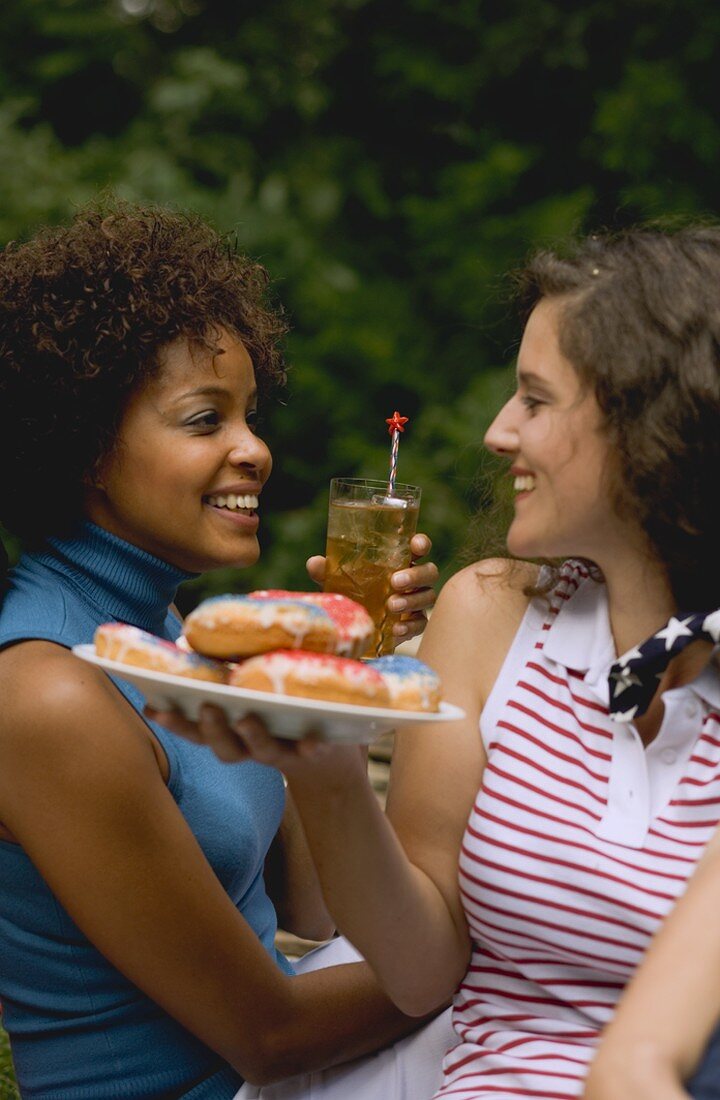 Two women with doughnuts & iced tea on the 4th of July (USA)