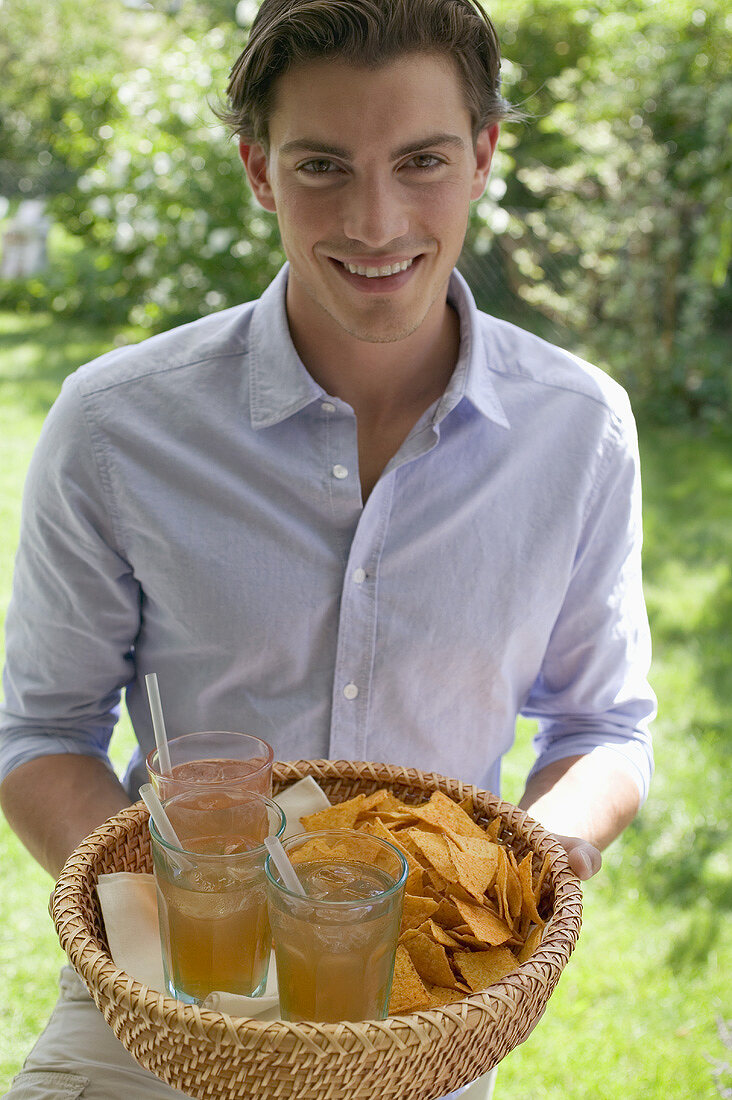 Man holding basket of drinks and tortilla chips