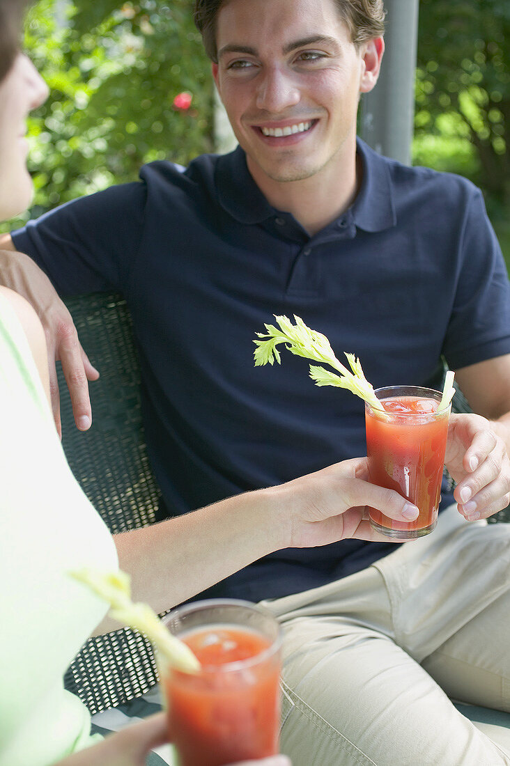 Woman handing tomato drink to young man