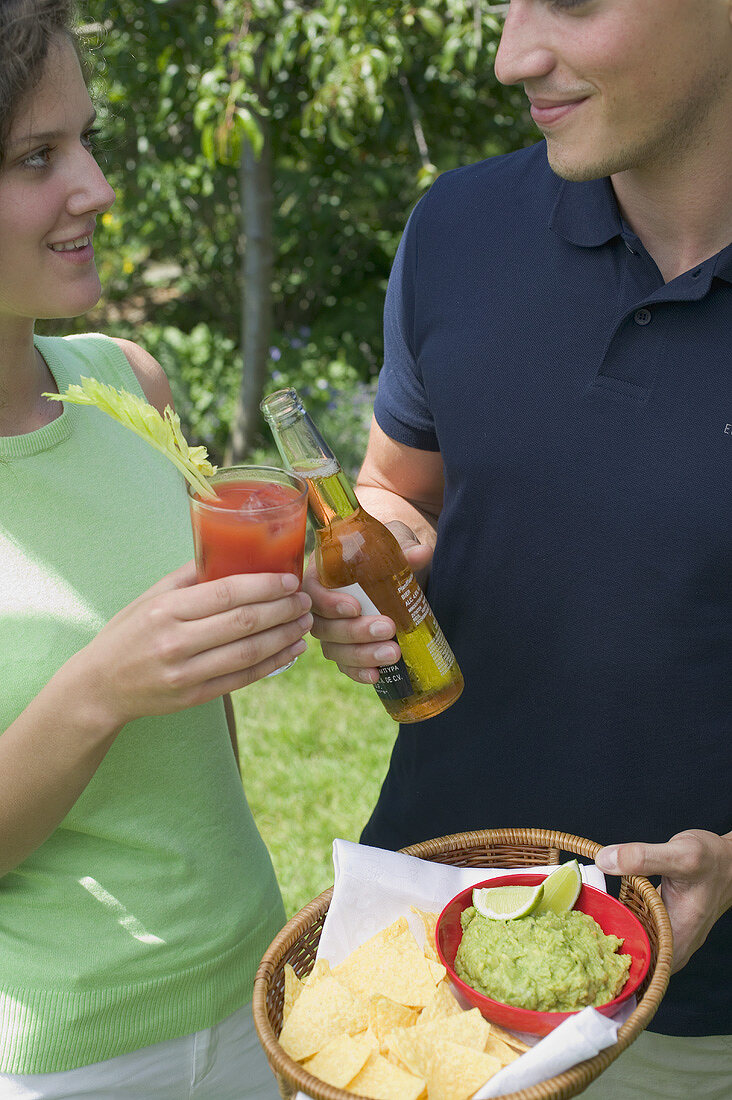 Young couple with guacamole, chips and drinks