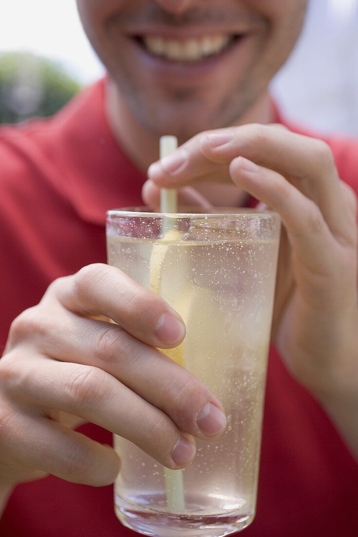 Man holding glass of lemonade with straw