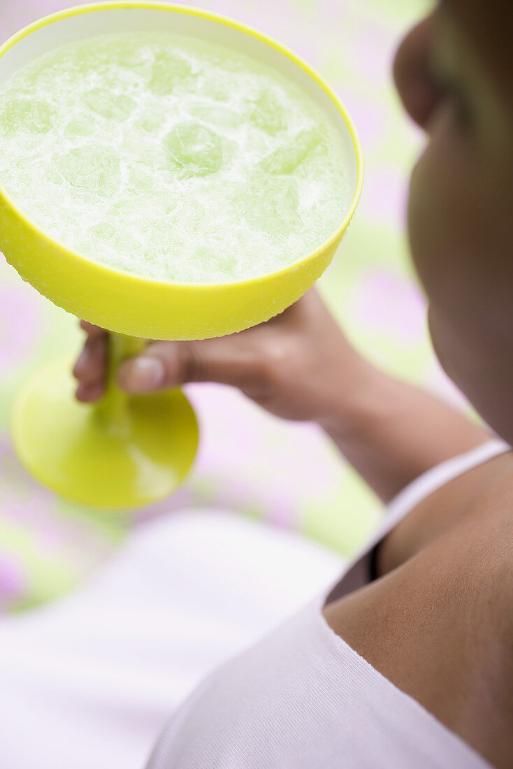 Woman holding a cocktail in a green glass