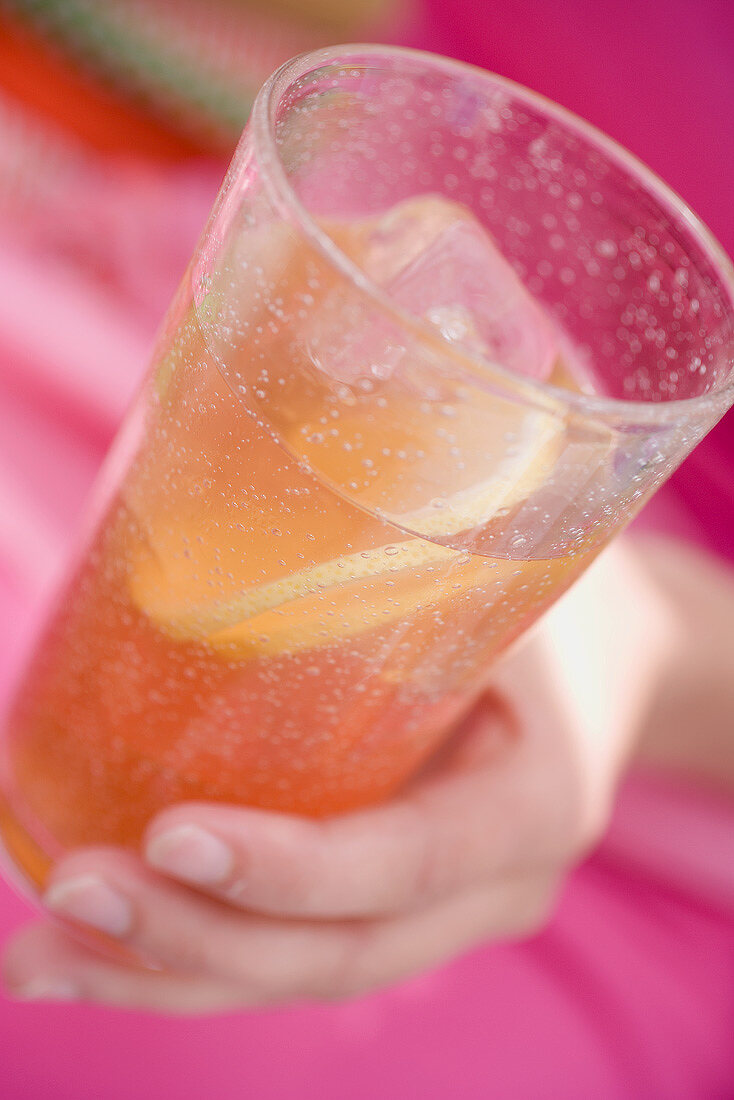 Hand holding a glass of iced tea