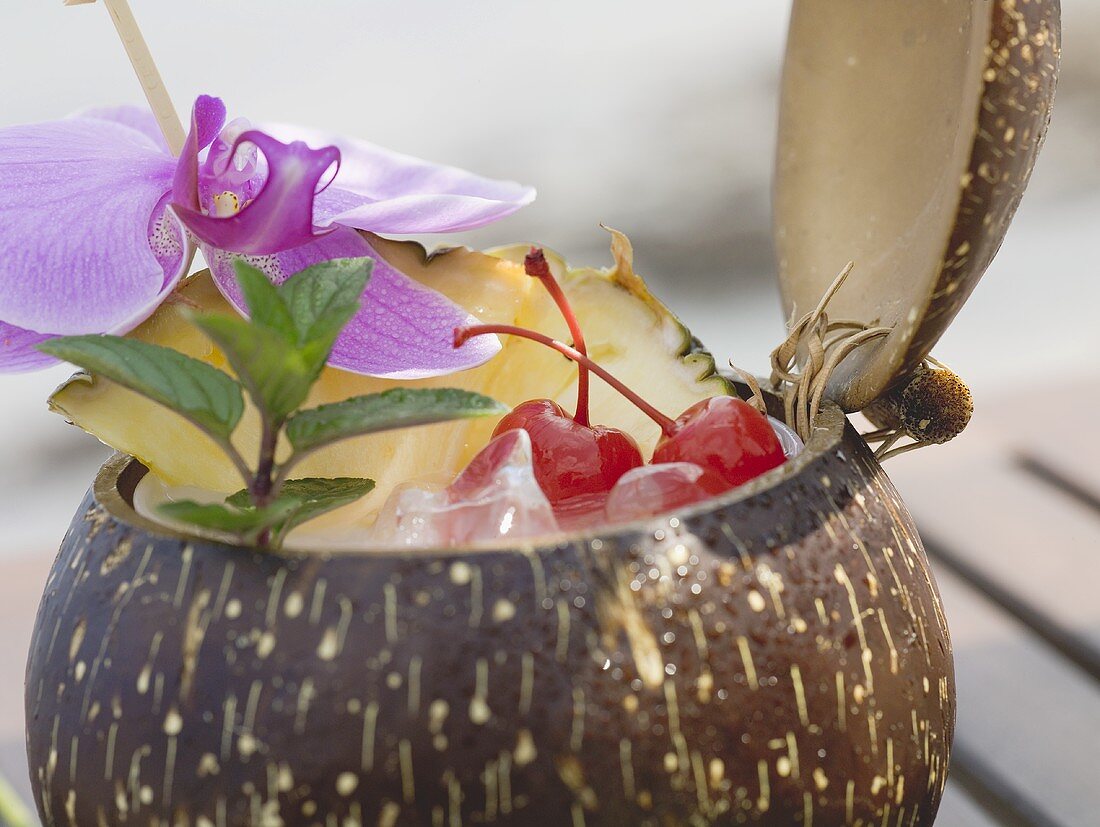 Coconut drink with pineapple, cocktail cherry and orchid