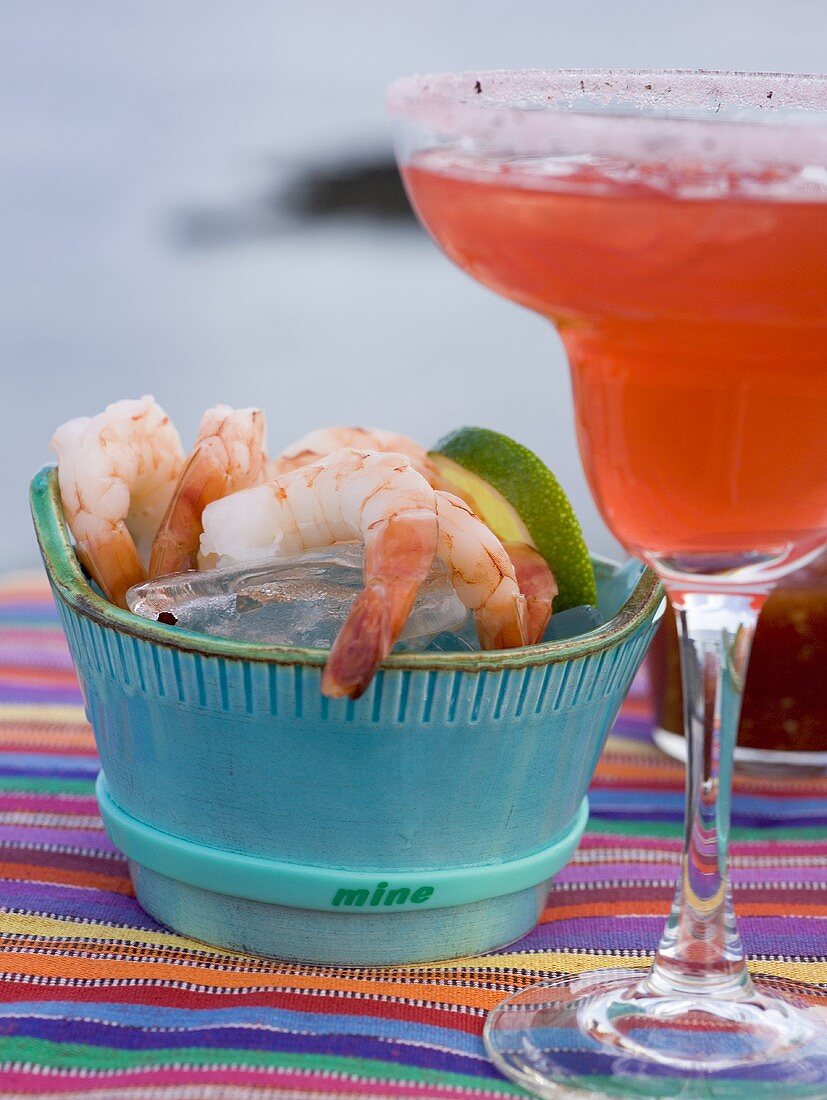 Roter Cocktail im Glas, daneben Shrimps mit Dip