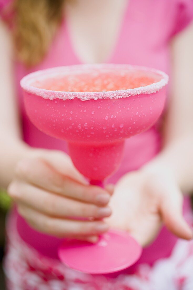 Frau hält pinkfarbenen Cocktail