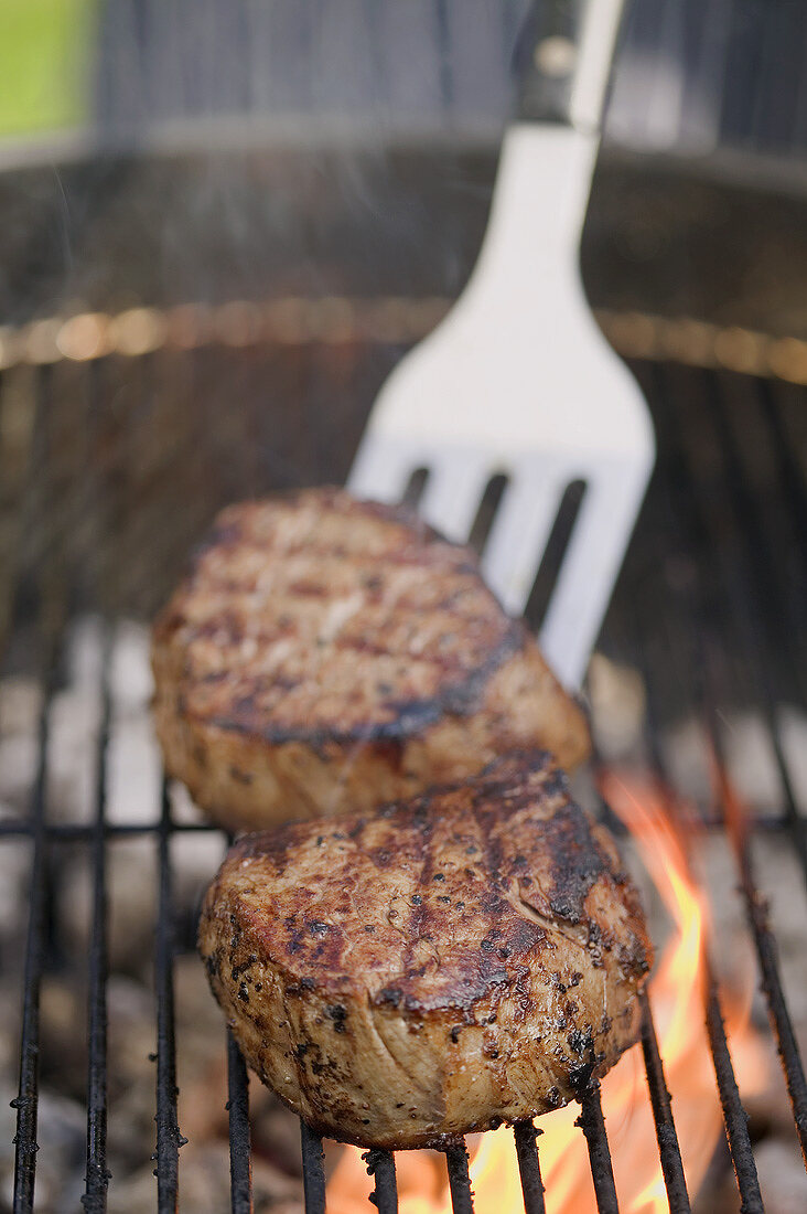 Beef medallions on a barbecue with spatula