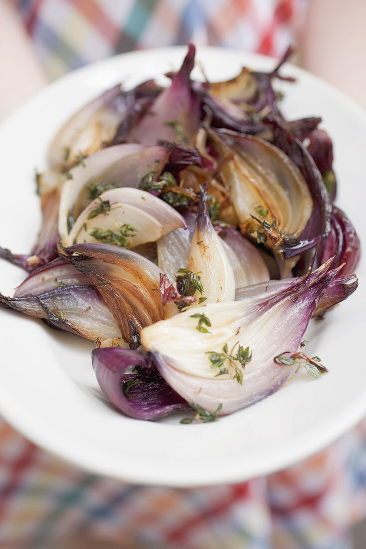 Woman holding a plate of grilled red onions (close-up)