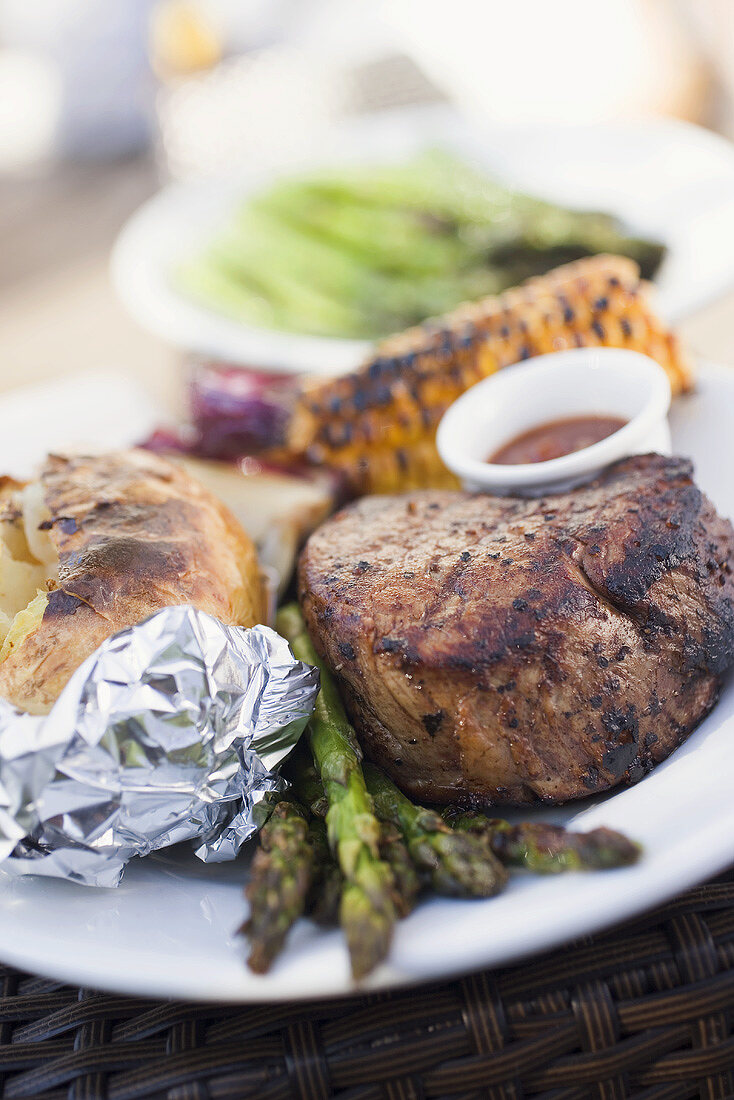 Grilled beef steak, asparagus, baked potato, corn on the cob