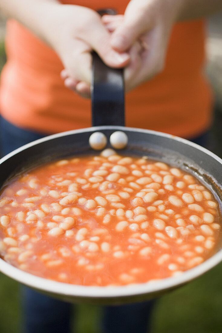 Person holding a pan of baked beans