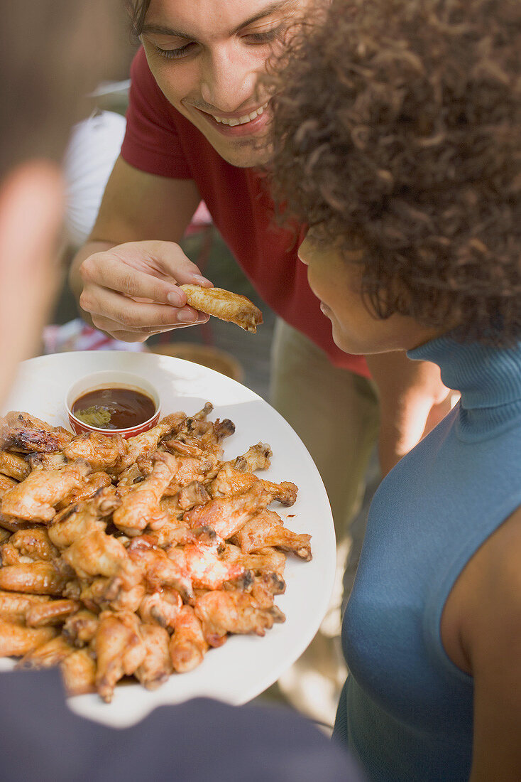 Man offering woman a taste of chicken wing