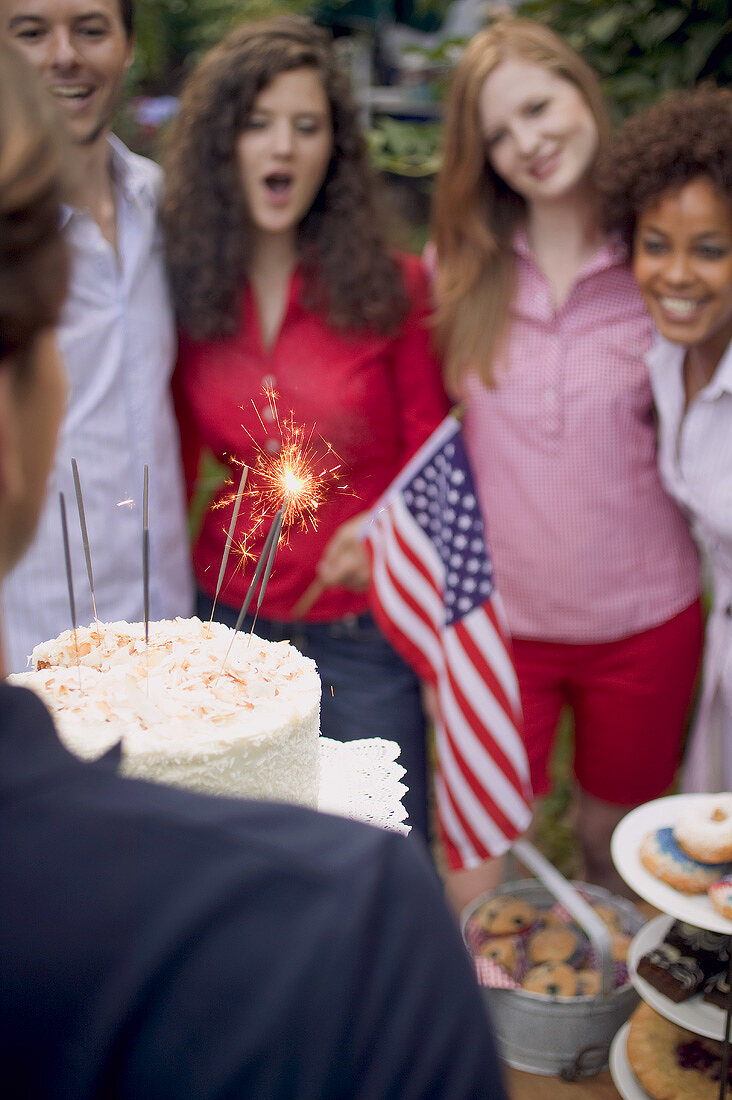 Man serving coconut cake with sparklers (4th of July, USA)