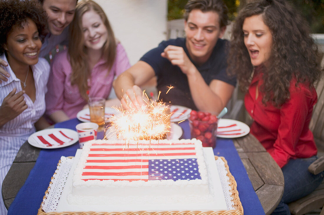 Man lighting sparklers on cake (4th of July, USA)