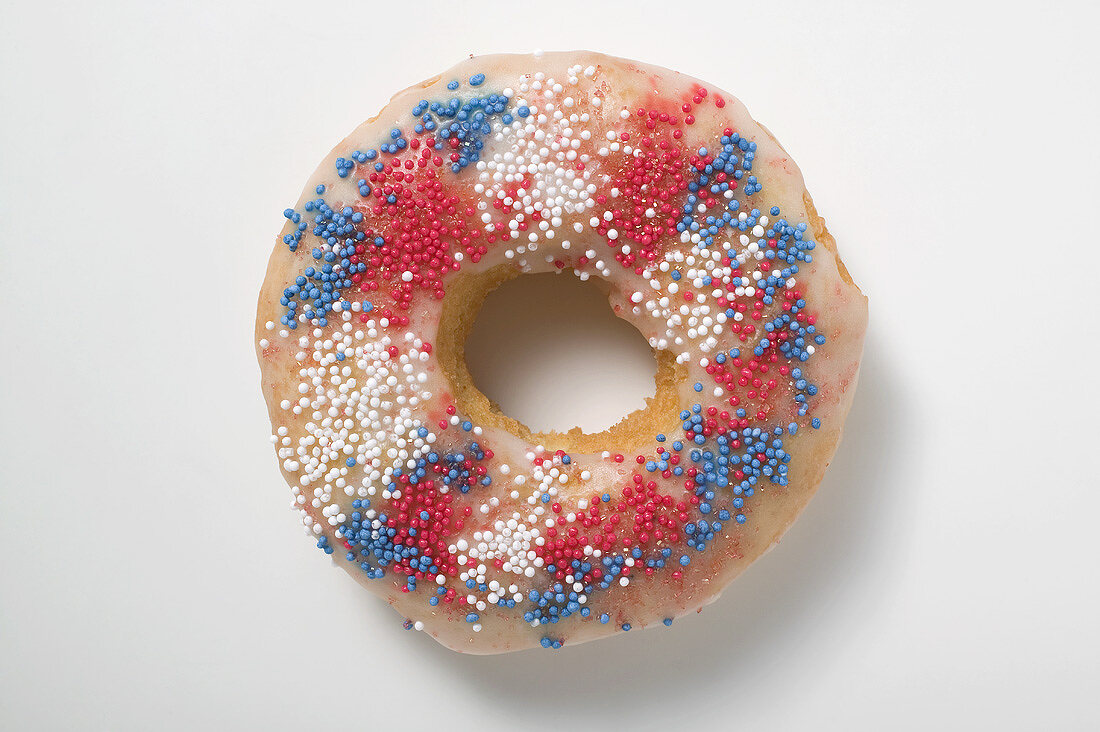 Doughnut mit Zuckerstreuseln in den Farben Rot, Blau, Weiß