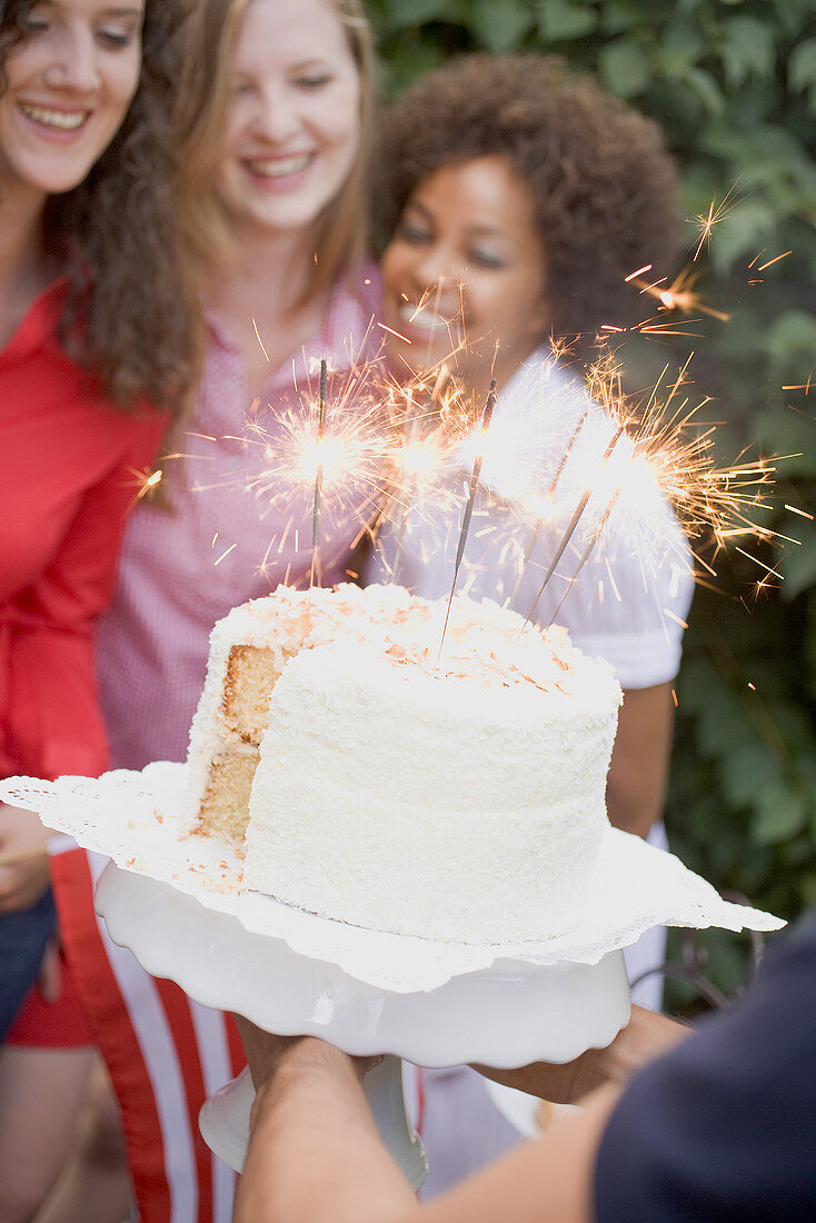 Man serving coconut cake with sparklers (4th of July, USA)