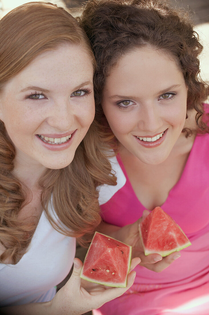Two women holding pieces of watermelon