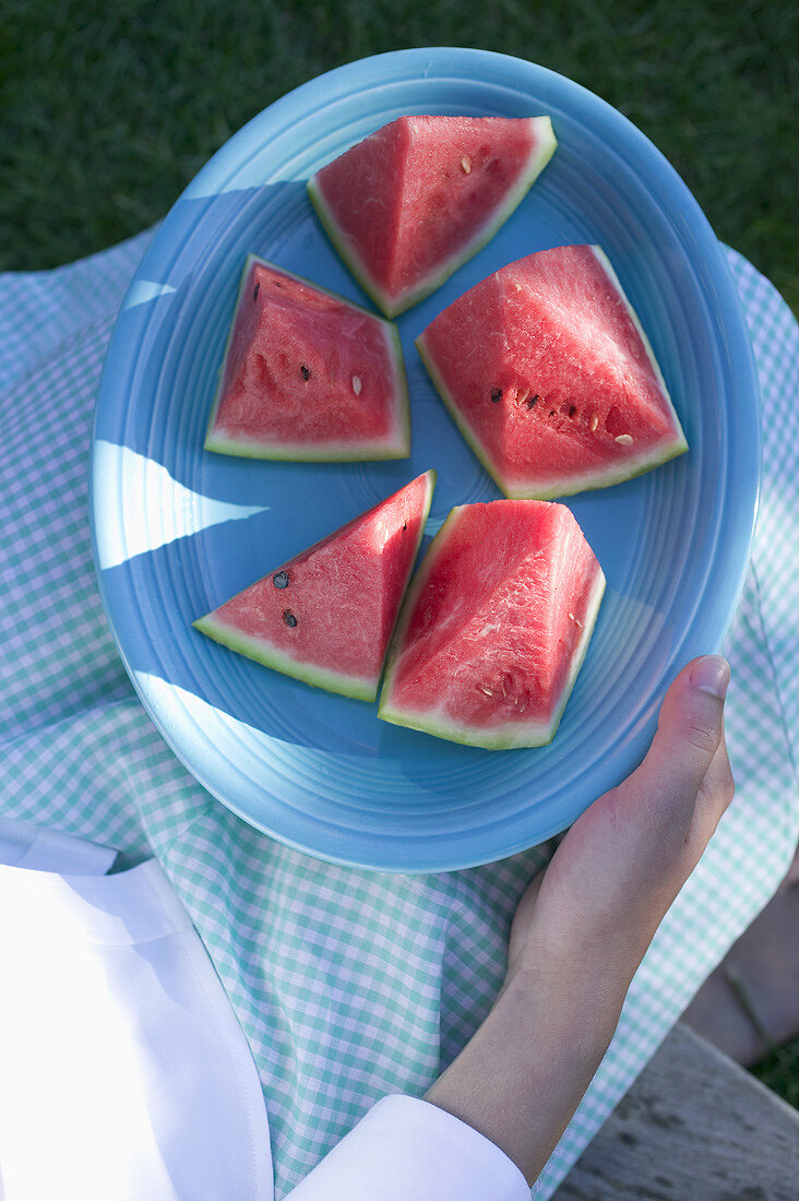 Woman holding a plate of watermelon wedges