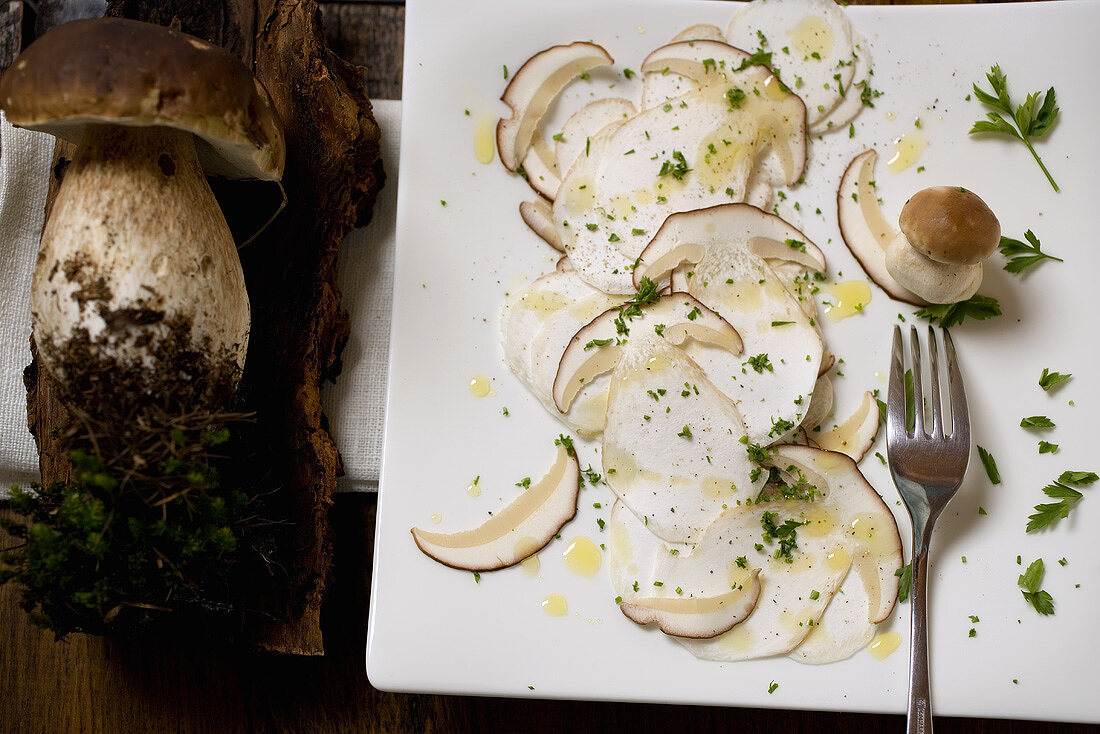 Steinpilzcarpaccio auf Schneidebrett und ganze Steinpilze