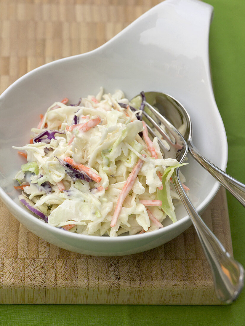 Coleslaw (cabbage salad, USA) in white bowl with cutlery