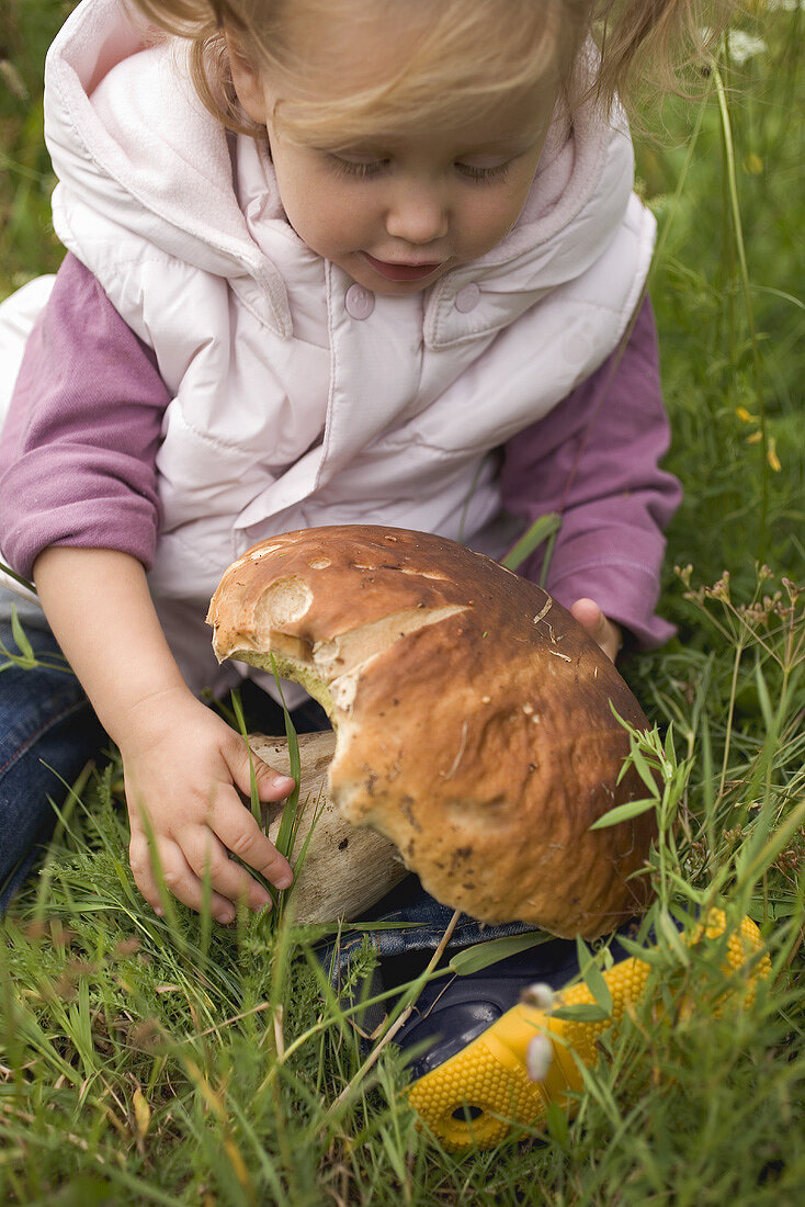 Small girl holding large cep in grass