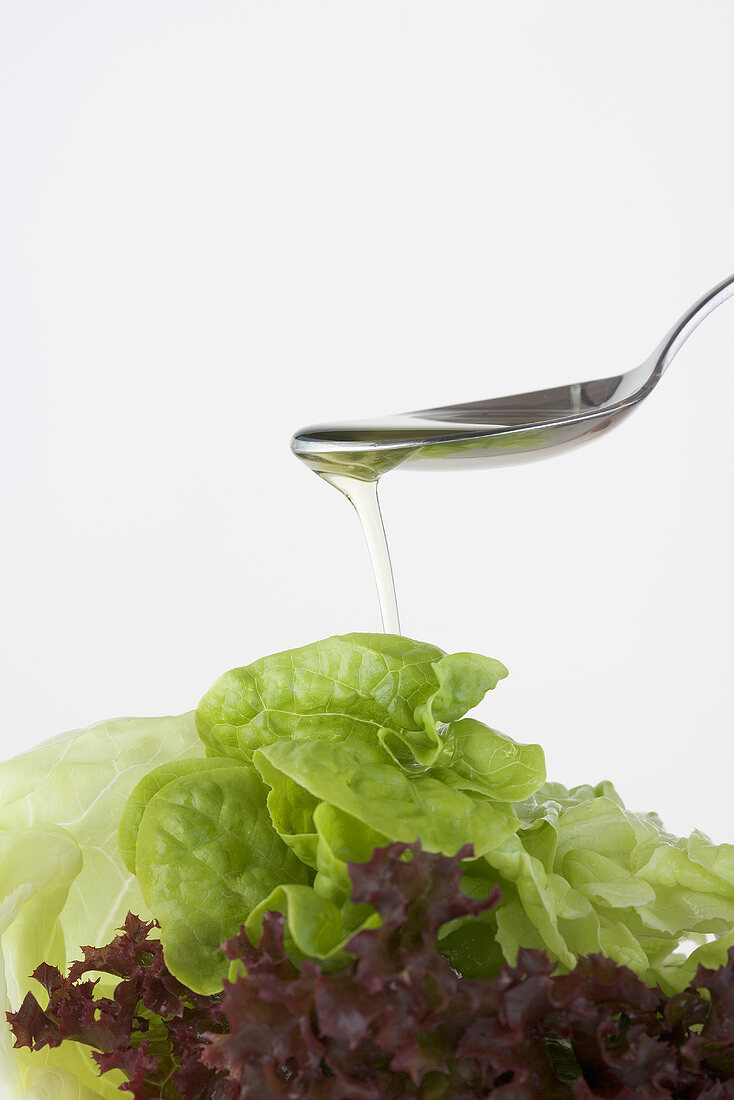Pouring oil onto mixed salad leaves